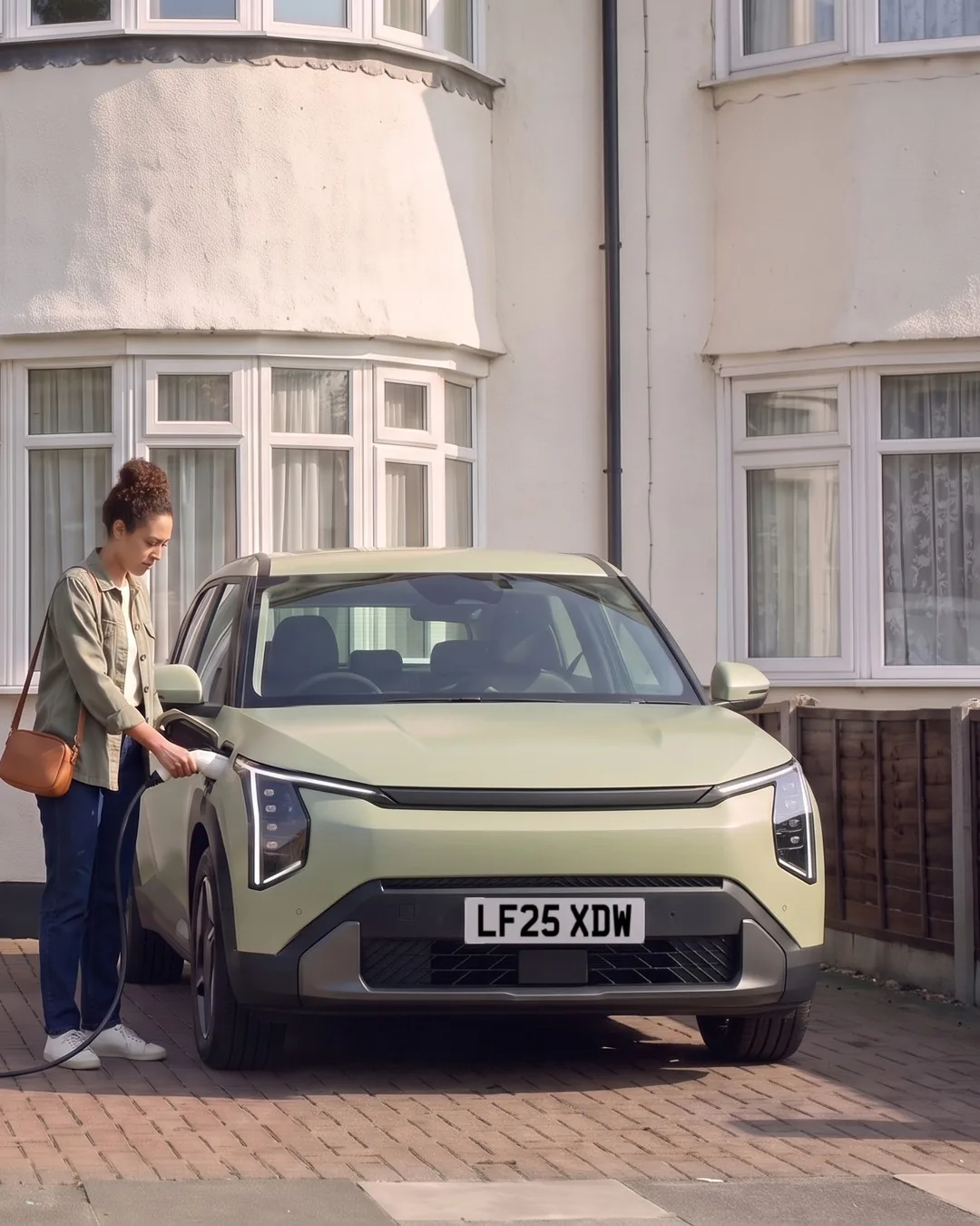 Maya plugging the charger's cable into her car on Martin's drive.