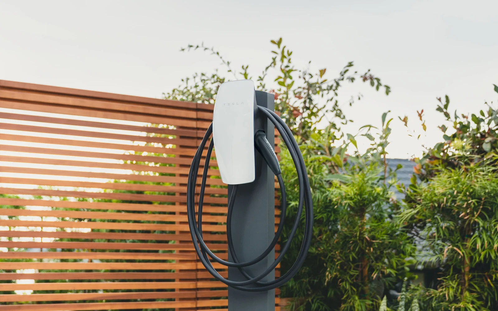 Tesla Wall Connector on a post in a garden